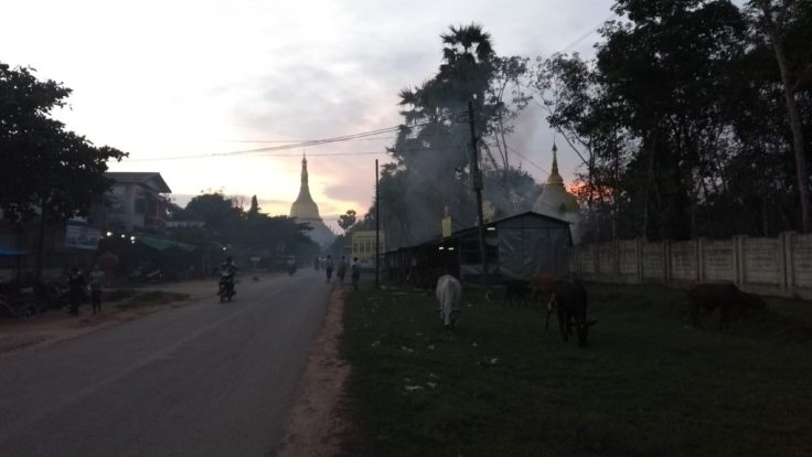 Walking back to Bago, smoke rises over a house, filtering the sunset