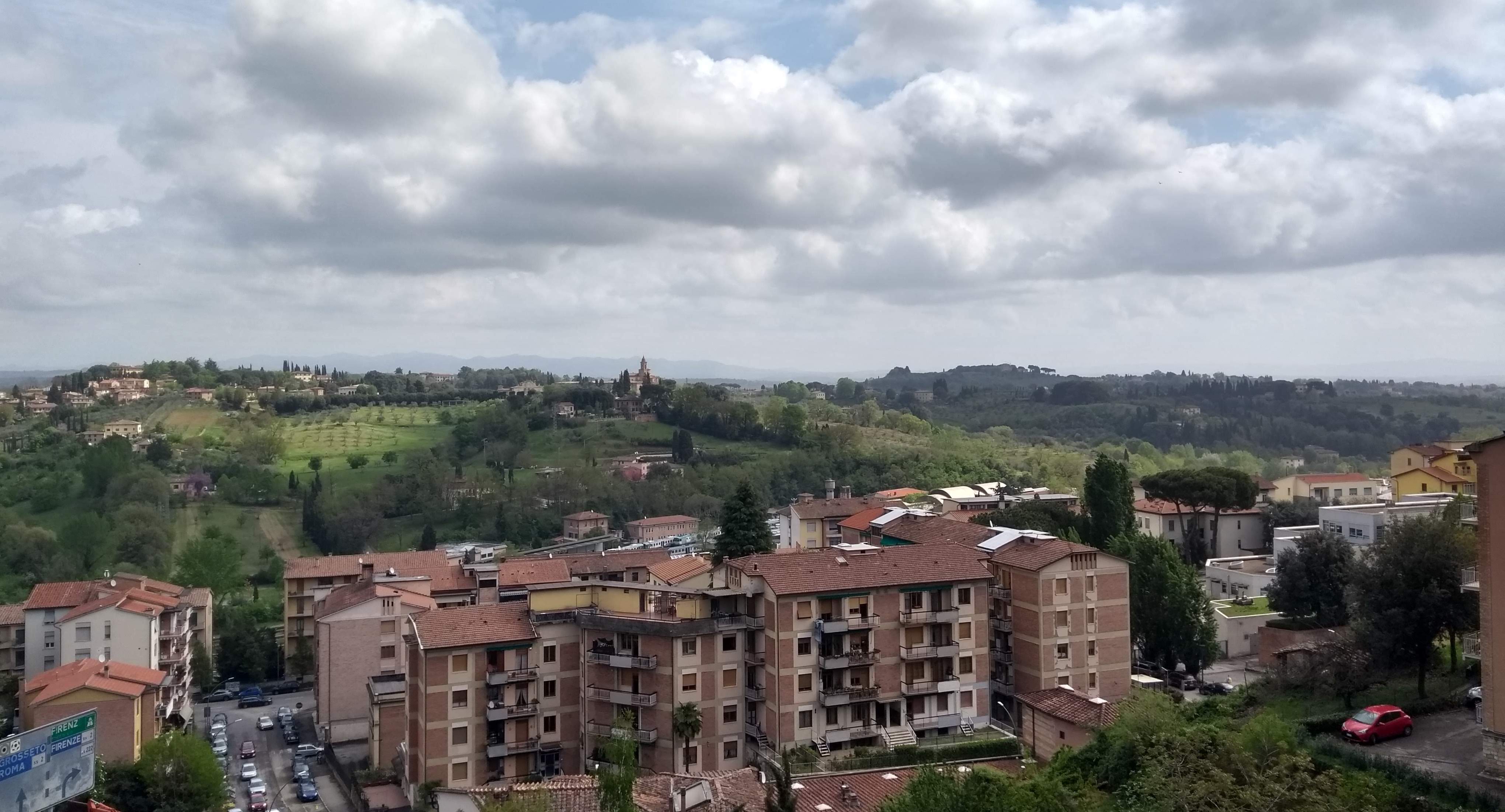 View over unlovely Siena flats, to green fields and forested hills beyond